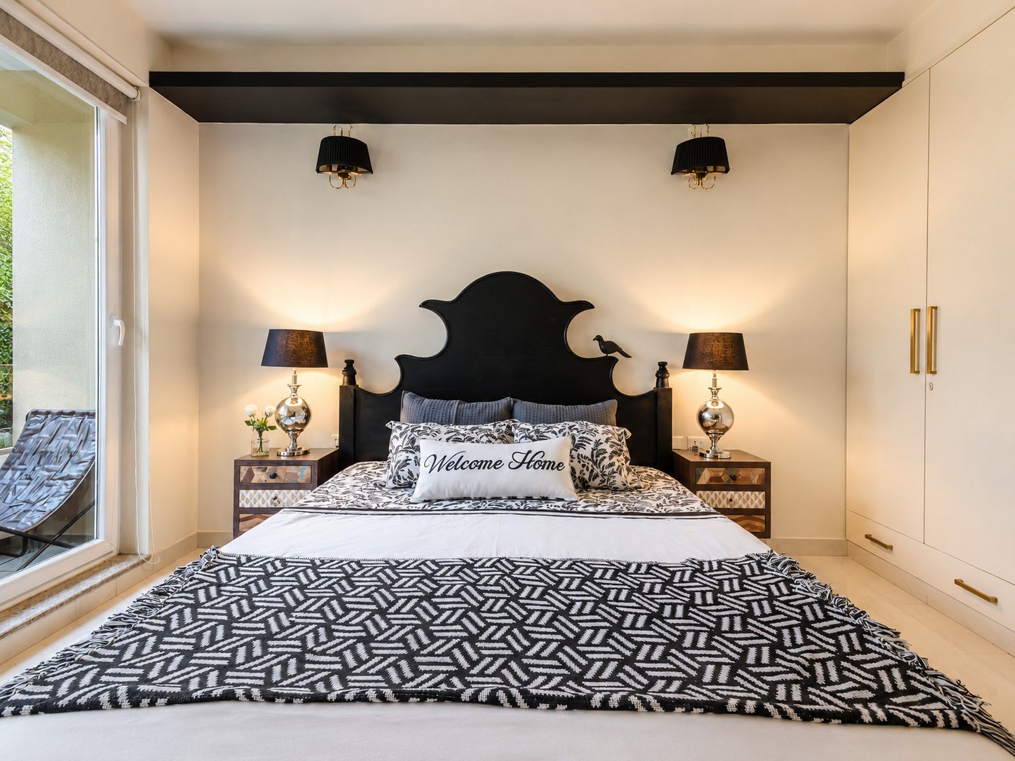 Bedroom with a distinctive headboard and broad green-facing windows.