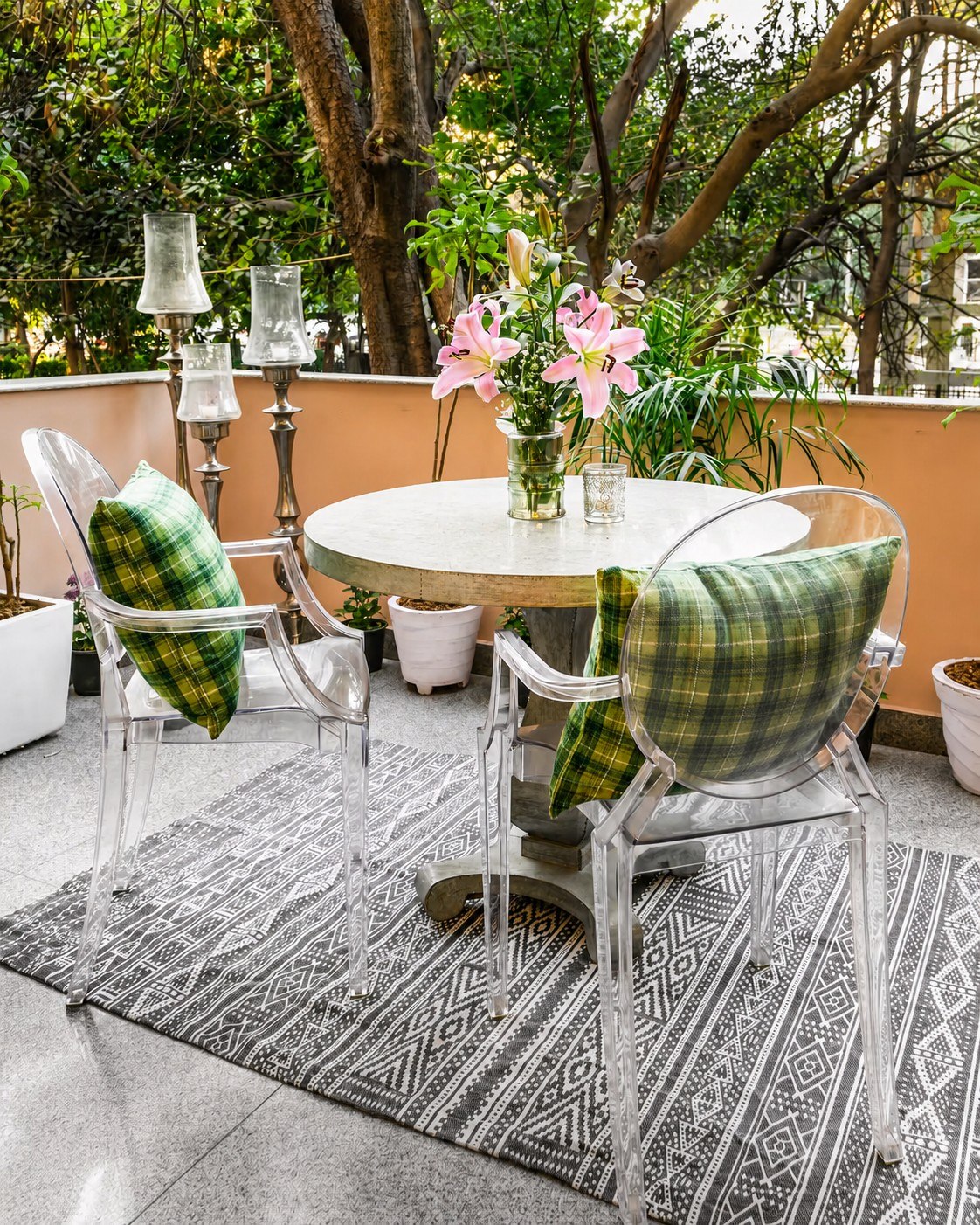 Outdoor dining setting with a round table, flowers, and greenery.