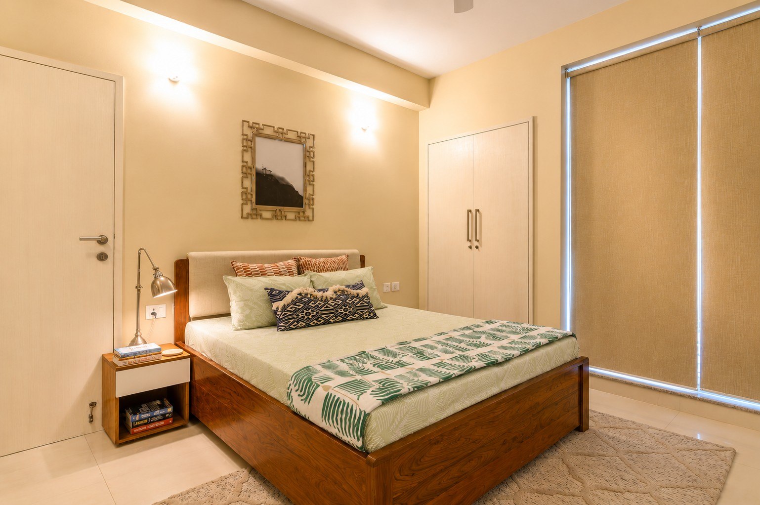 Bedroom with warm light, framed artwork, and built-in storage.