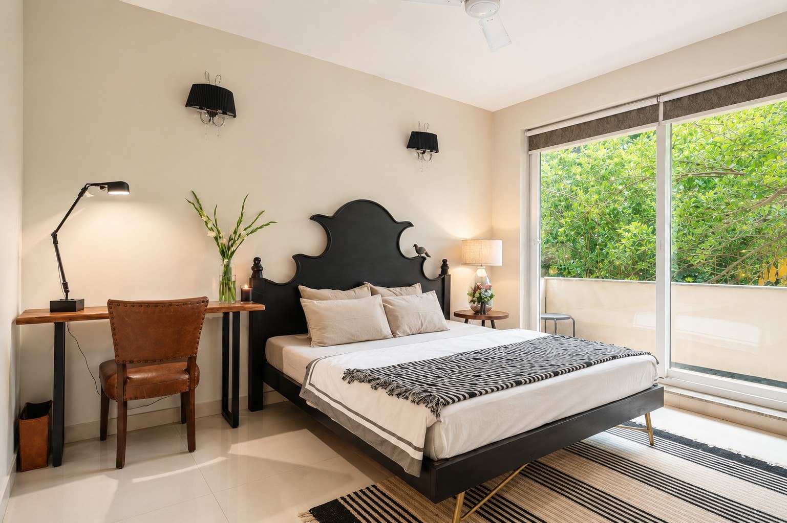 Bedroom view with work desk, patterned bedding, and window light.