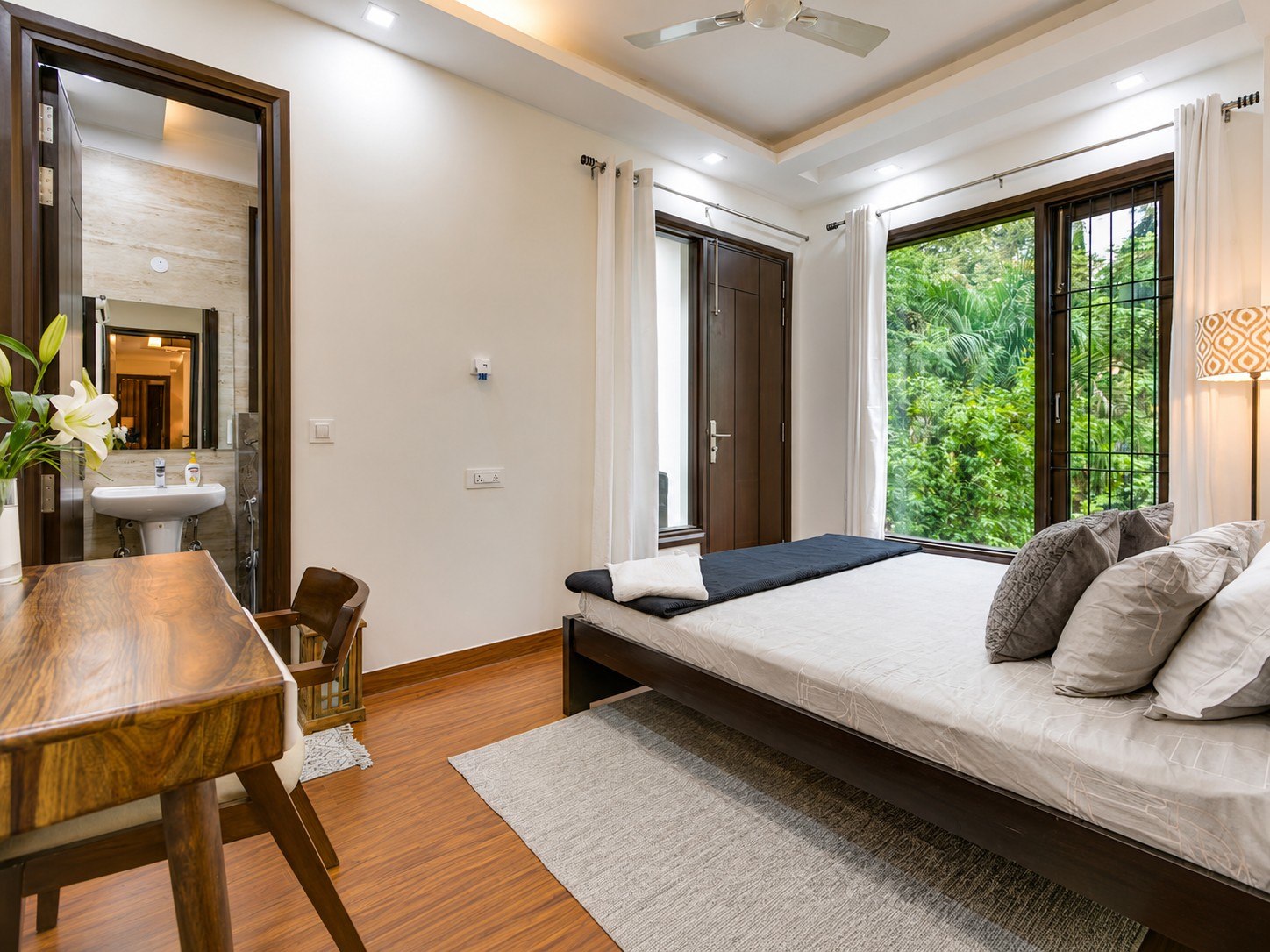 Bedroom with broad windows and an adjacent table or desk.