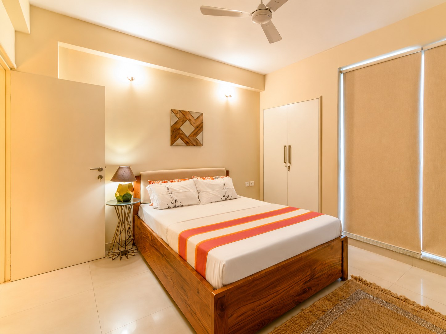 Bedroom with pale bedding, wardrobe, and window coverings.