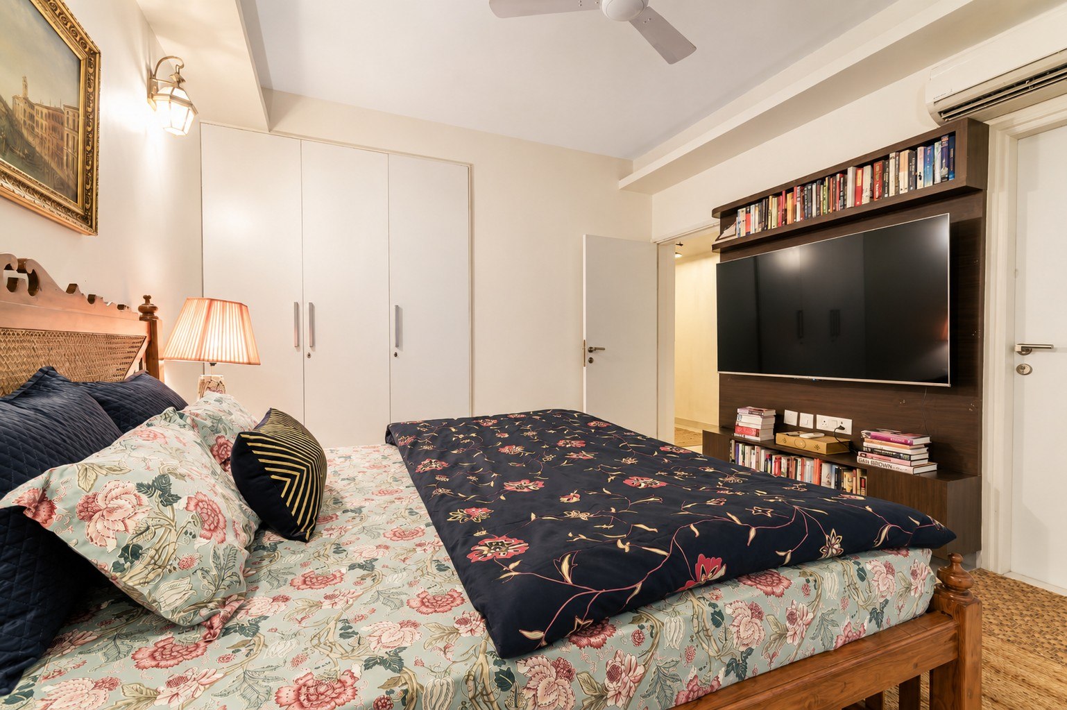 Bedroom view with media wall, patterned bedding, and natural light.